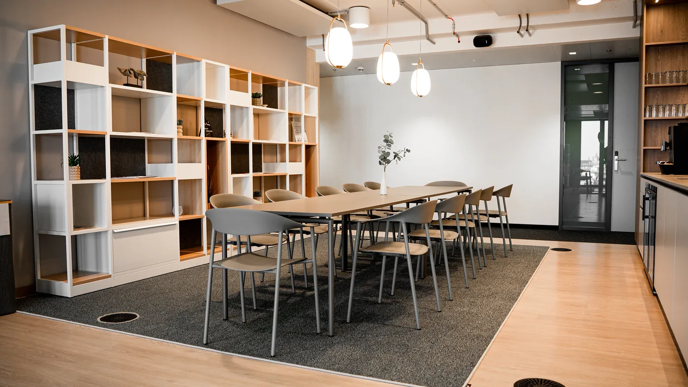 Tafel mit Stühlen, Regalwand und Pendelleuchten im SalesDrive-Büro