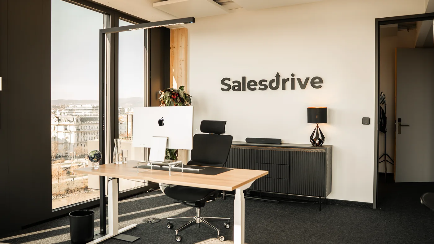 Arbeitsplatz vor der großen SalesDrive-Logowand im Büro in Wien