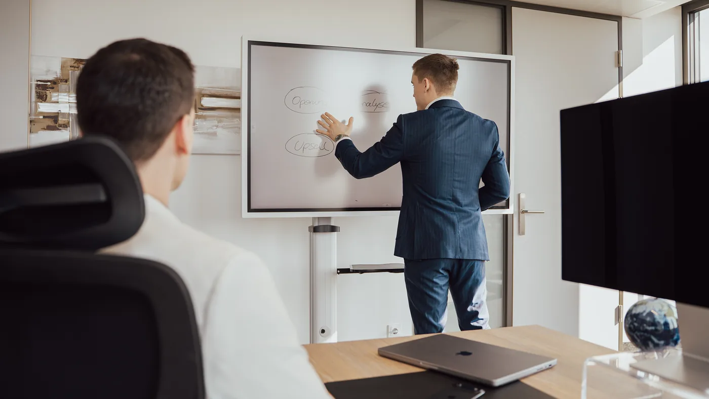 Lukas Lehner skizziert eine Kampagne am Whiteboard, ein Teammitglied hört zu